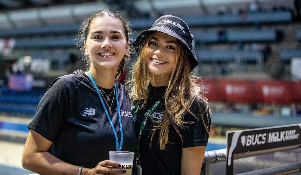 Two female students at swimming champs promoting milk every moment campaign